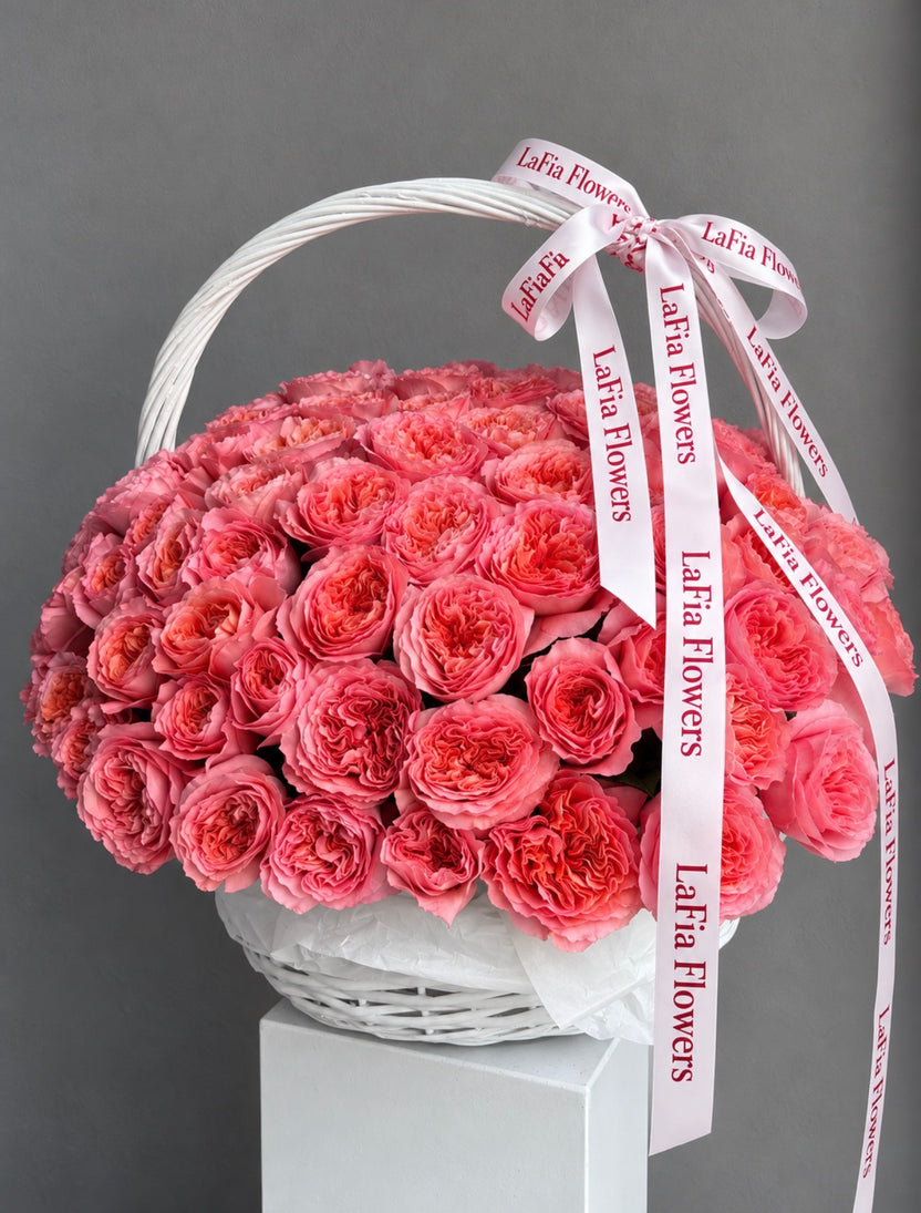 Side view of Blush Royale pink roses arranged in a white wicker basket