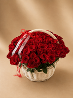 Red rose basket in white wicker with LaFia ribbon against a beige background