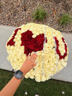 Close-up of white roses, red floral lettering, and LaFia ribbon on a custom arrangement
