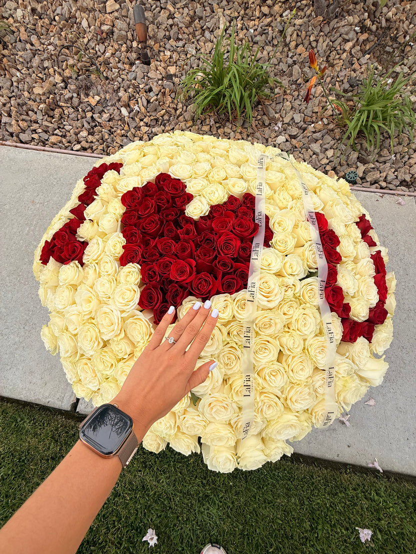 Close-up of white roses, red floral lettering, and LaFia ribbon on a custom arrangement